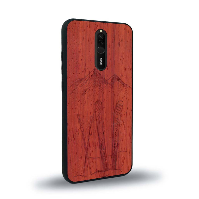 Coque de protection en bois véritable fabriquée en France pour Xiaomi Redmi 8 sur le thème de la montagne, du ski et de la neige avec un motif représentant une paire de ski plantée dans la neige avec en fond des montagnes enneigées