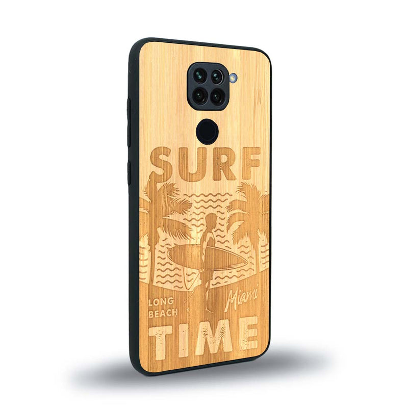 Coque de protection en bois véritable fabriquée en France pour Xiaomi Redmi Note 9 sur le thème chill avec un motif représentant une silouhette tenant une planche de surf sur une plage entouré de palmiers et les mots "Surf Time Long Beach Miami"